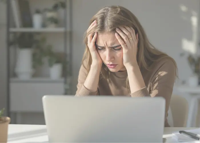 femme devant son ordinateur avec une expression découragée, dans un style professionnel et minimaliste